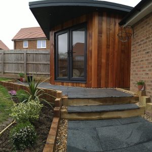 The Mallard Garden Room In St Albans - Completed Garden Room With Wooden Cladding, Glass Doors, And A Landscaped Stone Path And Steps