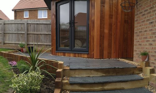 The Mallard Garden Room In St Albans - Completed Garden Room With Wooden Cladding, Glass Doors, And A Landscaped Stone Path And Steps