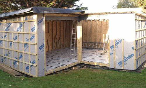 A partially built garage showcasing insulation being applied to the walls, indicating progress in the construction process