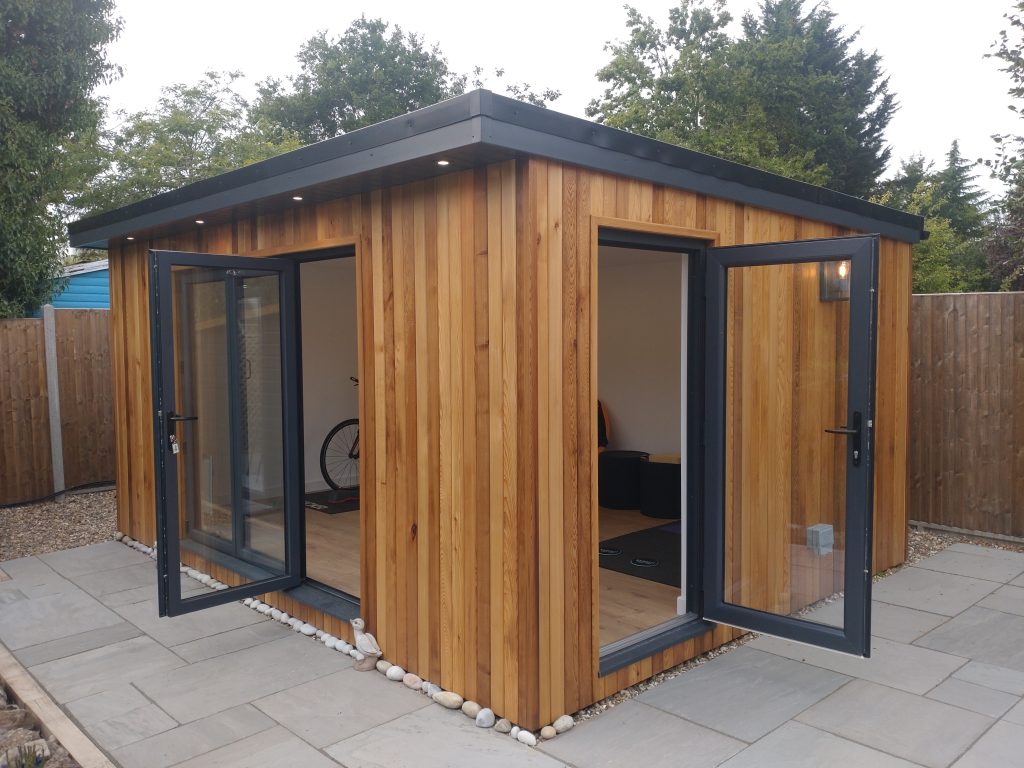 The Jenning Garden Room - A compact garden room with transparent doors, nestled among plants, ideal for a serene work environment