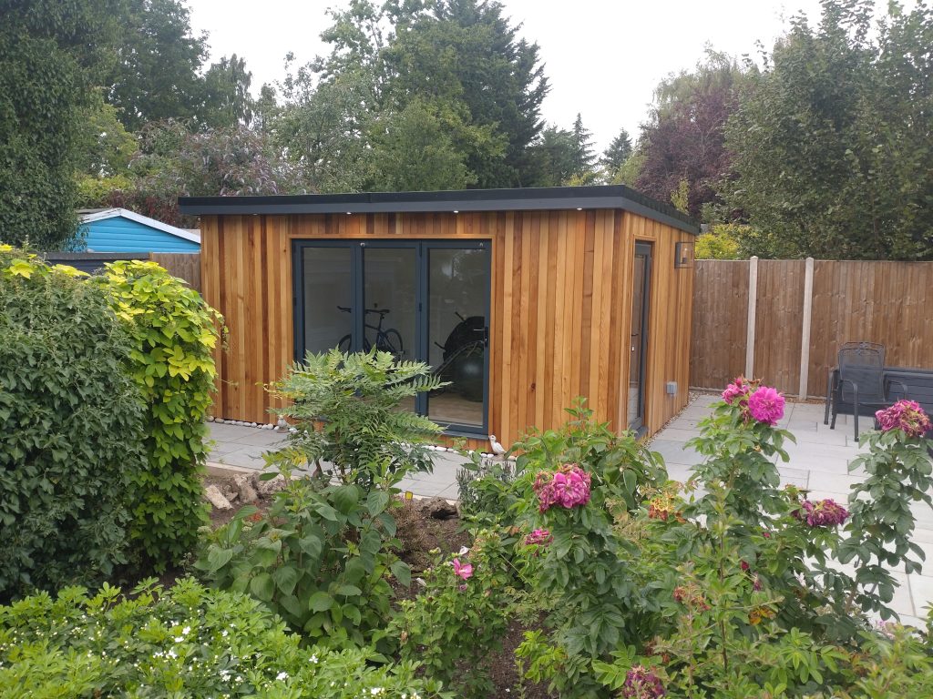 A serene garden room with warm wooden walls and a transparent glass door, blending indoor and outdoor environments